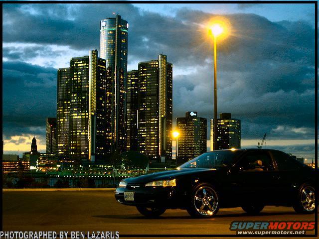 1997 Ford Thunderbird coupe, side view, parked with Detroit skyline in background