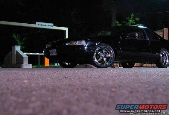 1997 Ford Thunderbird coupe with aftermarket chrome wheels parked at night