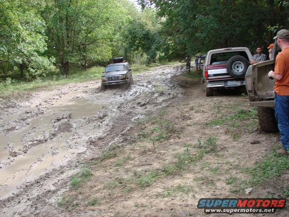 Dark 1996 Ford Bronco splashing through mud on a trail