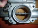 1993 Mazda MX-3 - Close-up of a throttle body, showing internal components and metallic construction.