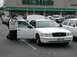 1998 Ford Crown Victoria - A white 1998 Ford Crown Victoria is parked with its doors open, showing people interacting with the vehicle.