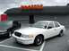1998 Ford Crown Victoria - A white 1998 Ford Crown Victoria is parked in front of a Hooters restaurant, with another dark sedan to its left.