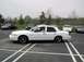 1998 Ford Crown Victoria - Side view of a white 1998 Ford Crown Victoria with a driver inside, parked in a lot.