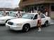 1998 Ford Crown Victoria - Two white Ford Crown Victorias are parked in front of a building with two women standing next to them.