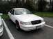 1998 Ford Crown Victoria - A white 1998 Ford Crown Victoria is parked in a lot, viewed from the front three-quarter angle.