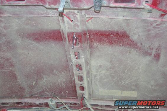 underside of a red hood with some wiring and a metal support beam