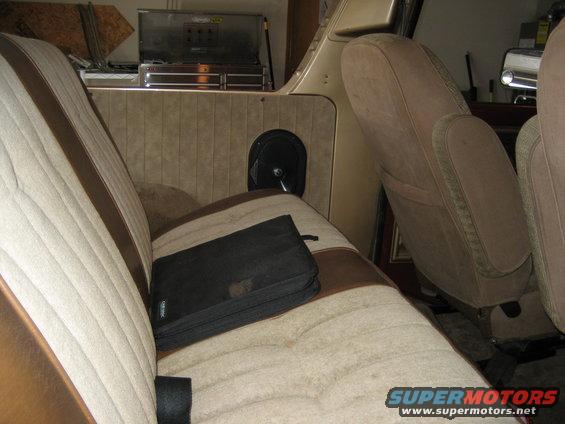 Interior shot of a vehicle showing seats, door panel with speaker, and storage compartment