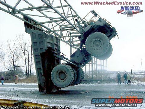Truck wedged in metal structure, large tires visible