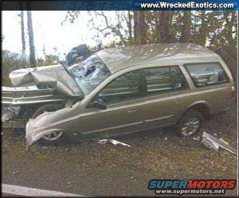 Gold station wagon with severe front-end damage, side view