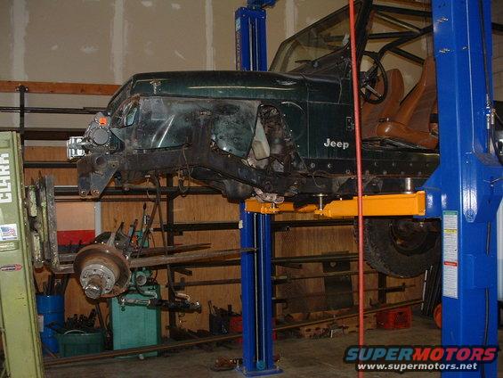 Jeep YJ on lift, front end removed, undergoing repairs in a garage