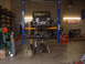1994 Jeep YJ - A Jeep Wrangler is suspended on a lift in a garage, undergoing maintenance with its rear axle detached.