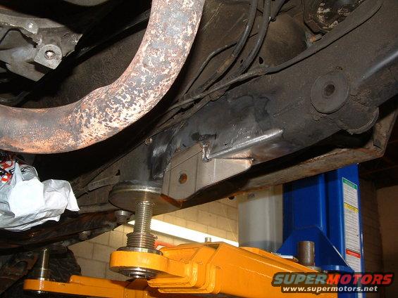Underside of a vehicle on a lift, showing exhaust pipe and frame modifications