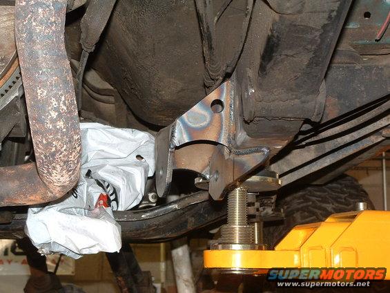 underneath vehicle frame with new metal brackets welded on, supported by a yellow jack