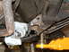 1994 Jeep YJ - Custom metal brackets are being welded onto the vehicle's frame, with a jack providing support.
