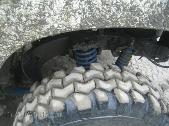 Mud-covered tire and blue suspension spring on an off-road vehicle