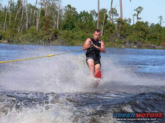 Person water skiing behind a boat, creating a large spray