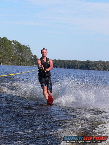 Man waterskiing on a lake, pulled by a boat. Water is splashing