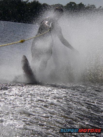 Water skier spraying water while being pulled by a rope