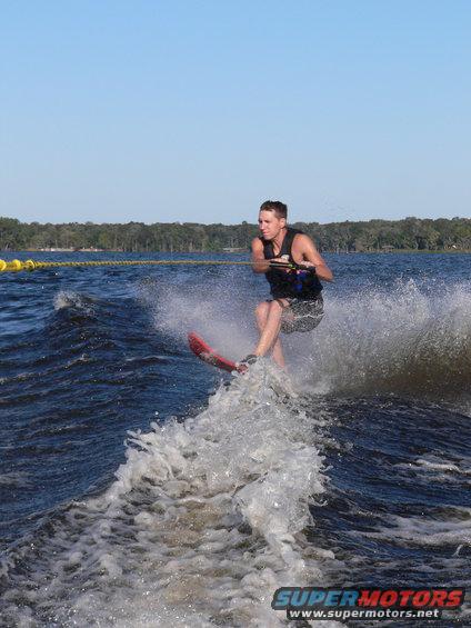 Person waterskiing behind a boat, creating a large wake