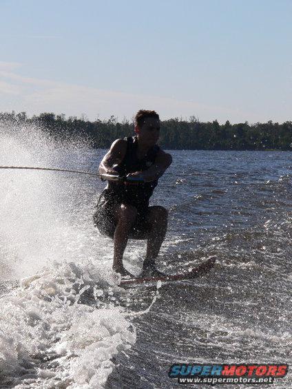 Waterskier in action on a lake, creating a large spray of water. A watermark reads SUPER MOTORS