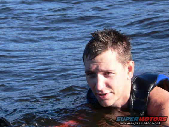 Man wearing a life vest in blue water, with a "SUPERMOTORS" logo visible