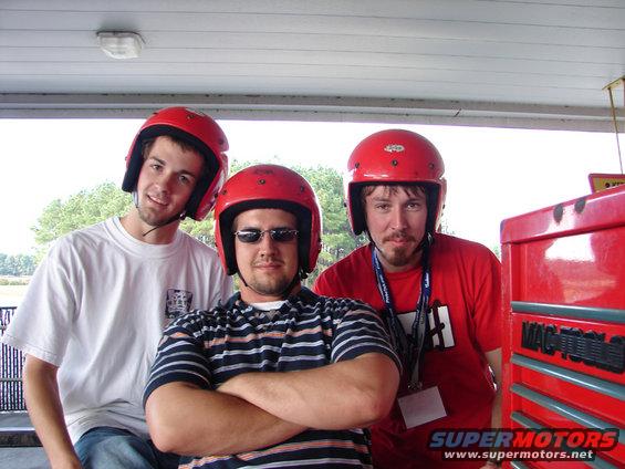 Three guys in red helmets pose for a photo next to a red toolbox