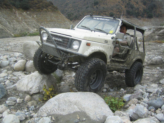 White 1987 Suzuki Samurai navigating rocky terrain