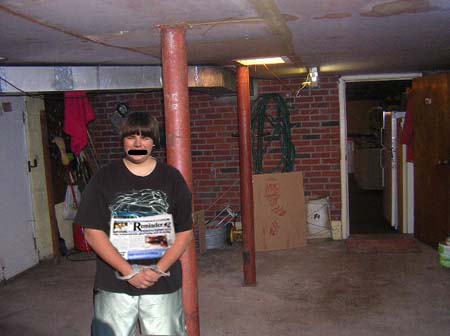 Person in handcuffs holding a newspaper in a basement