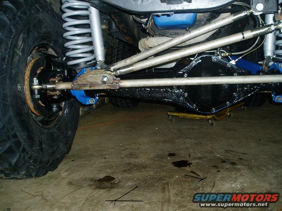 Close-up of a vehicle's front axle, suspension, and differential with large tires