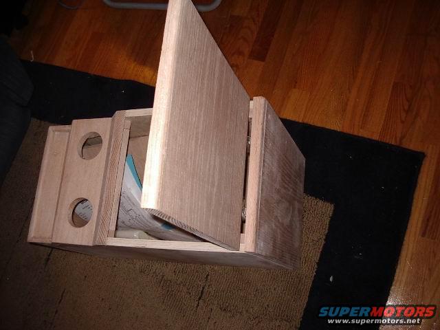 Wooden center console with open lid and two circular cutouts, sitting on a rug