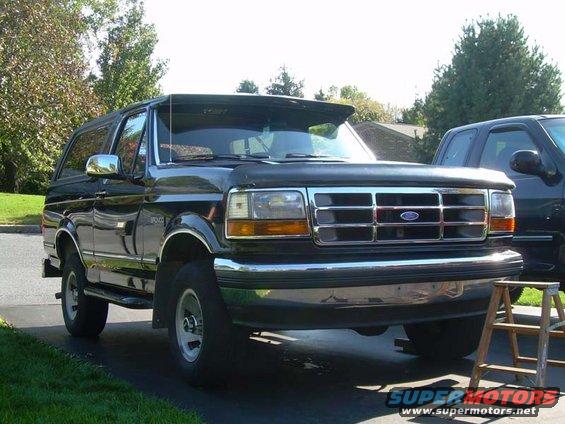 Black Ford Bronco parked in driveway, another truck next to it