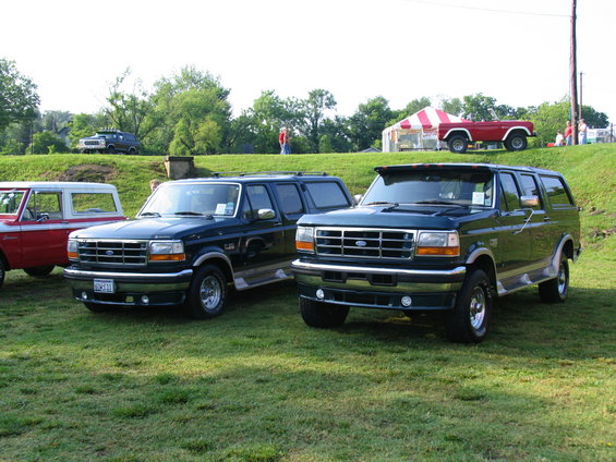 Two dark green Ford Broncos parked on grass, front view