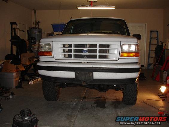 White Ford truck front view in garage. Grille has horizontal bars and a blue Ford emblem
