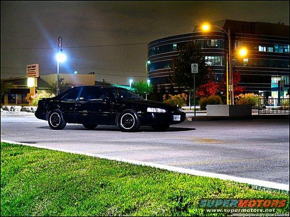 Black coupe parked at night, 3/4 front view