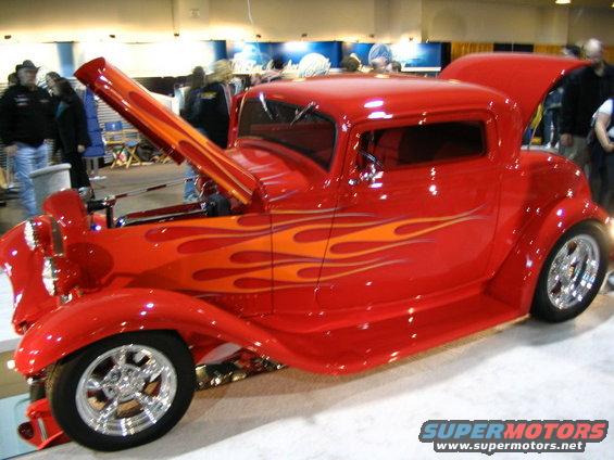 Red hot rod with orange flame decals, hood and trunk open, chrome wheels