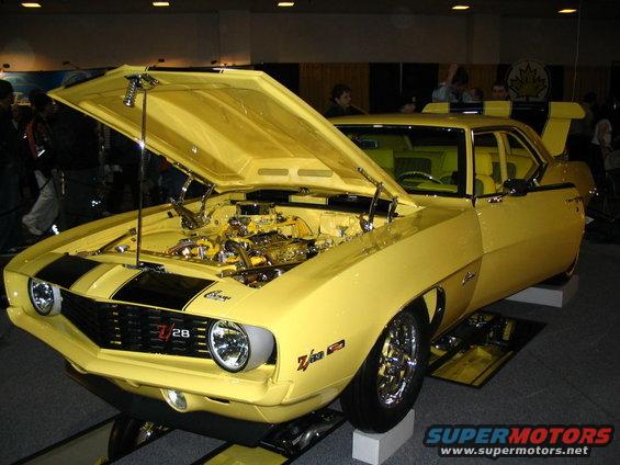 Yellow 1969 Chevrolet Camaro Z28 with black stripes, hood open revealing engine