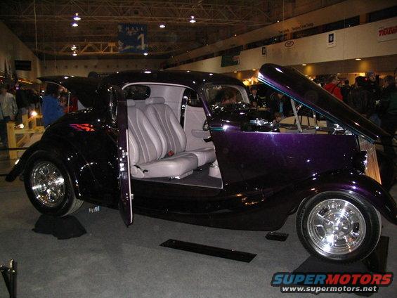 Custom coupe hot rod with purple paint, doors open, showing light gray interior and engine compartment