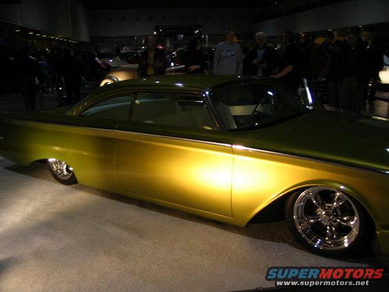 Customized classic car with gold paint and chrome wheels, seen from the side