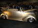 1993 Ford Taurus - A gold convertible is displayed with its hood open, revealing the engine bay, at an indoor event.