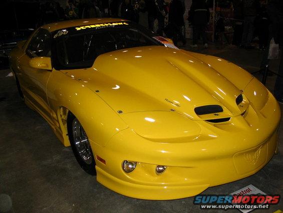 Yellow Pontiac Firebird with a large hood scoop and racing decals on the windshield