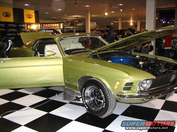 Lime green 1970 Ford Mustang coupe with white interior, hood open, on display