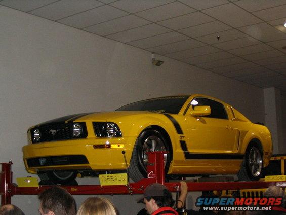 Yellow Ford Mustang GT on a lift with black stripes