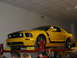 1993 Ford Taurus - A yellow Ford Mustang GT is displayed on a lift, showing its distinctive racing stripes and GT badging.
