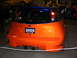 1993 Ford Taurus - Orange hatchback with custom body kit and dual exhaust, seen at a car show. The license plate indicates 2005.