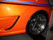 1993 Ford Taurus - Close-up of an orange car's side panel a custom chrome wheel and a black vent insert.