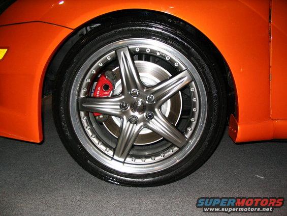 Close-up of a custom five-spoke wheel with a red brake caliper on an orange vehicle