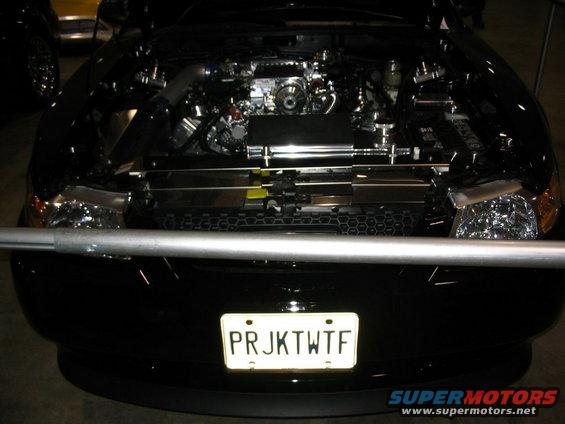 Black car engine bay with chrome accents and a custom license plate