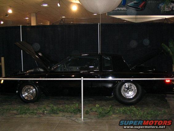 Black coupe with hood and trunk open, showing drag racing wheels