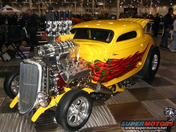 Yellow hot rod with exposed engine and chili pepper flames on the side