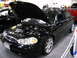 1993 Ford Taurus - Black sedan with hood open, parked indoors next to other vehicles.